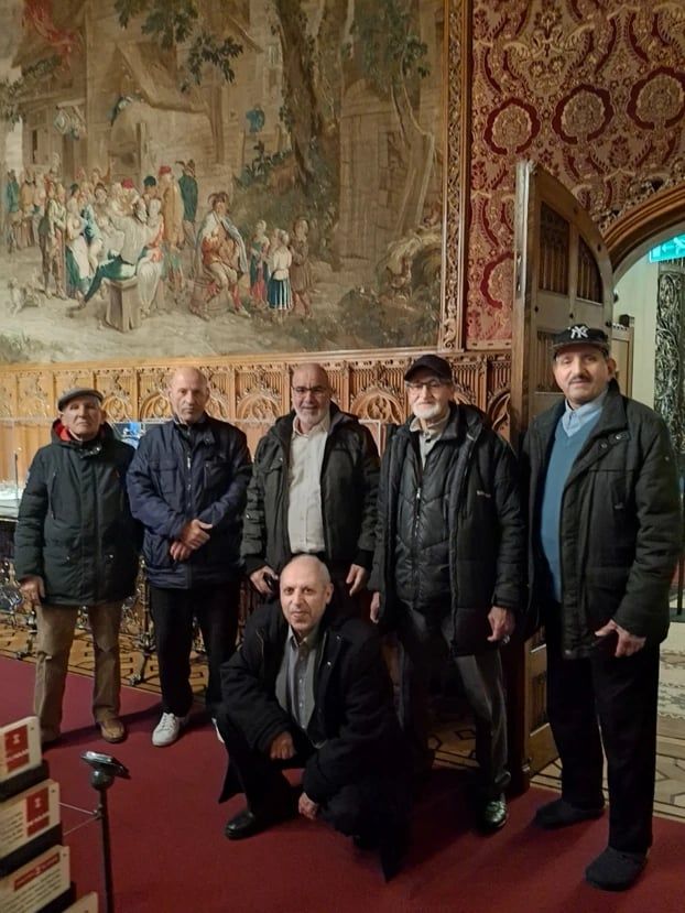 Deelnemers staan samen in een zaal van het kasteel, met een groot wandtapijt achter hen.