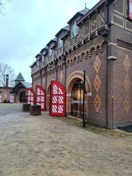 Een bijgebouw van het kasteel met rode deuren en metselwerk in patronen.